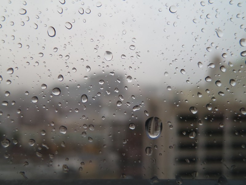 Image of cityscape seen through a window with raindrops on it.