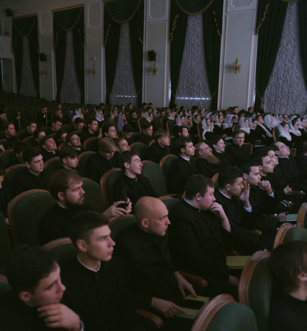 Image of auditorium with young students facing a stage.