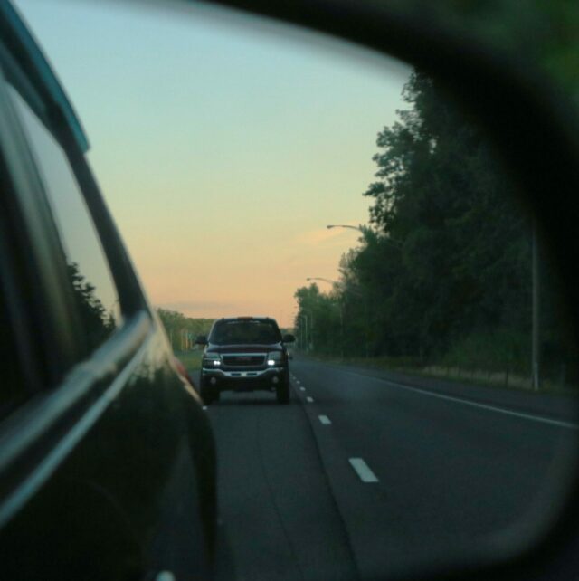 Image of car on highway in rearview window.